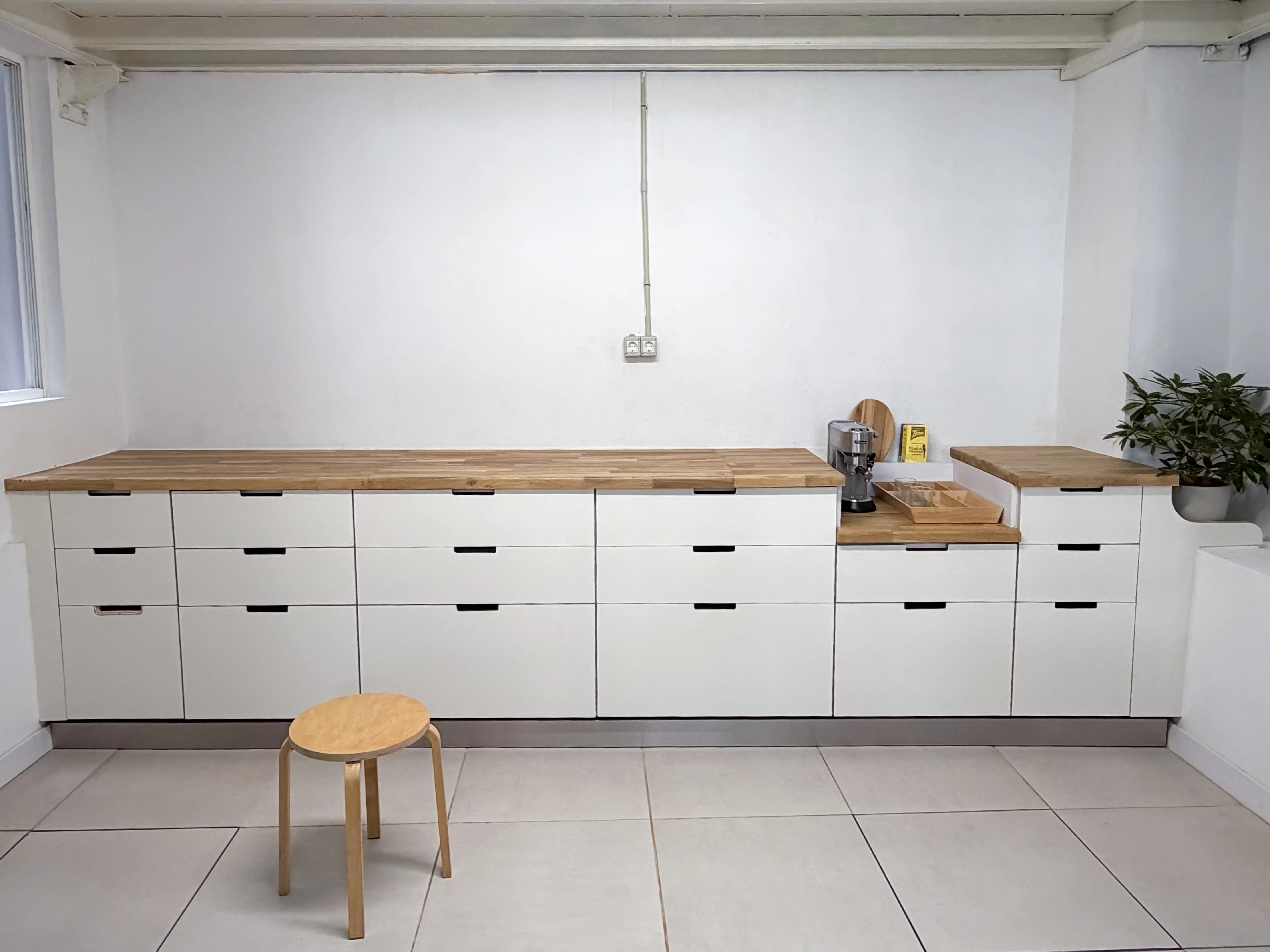Mueble de cajones blancos con encimera de roble macizo y un módulo cafetero a dos alturas